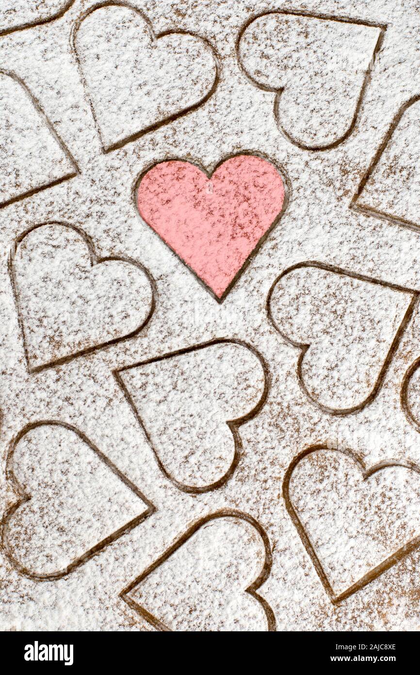 Zucker Herzform Cookies mit einem roten Herz, gekrönt mit Zucker Pulver, zum Valentinstag Hintergrund Stockfoto