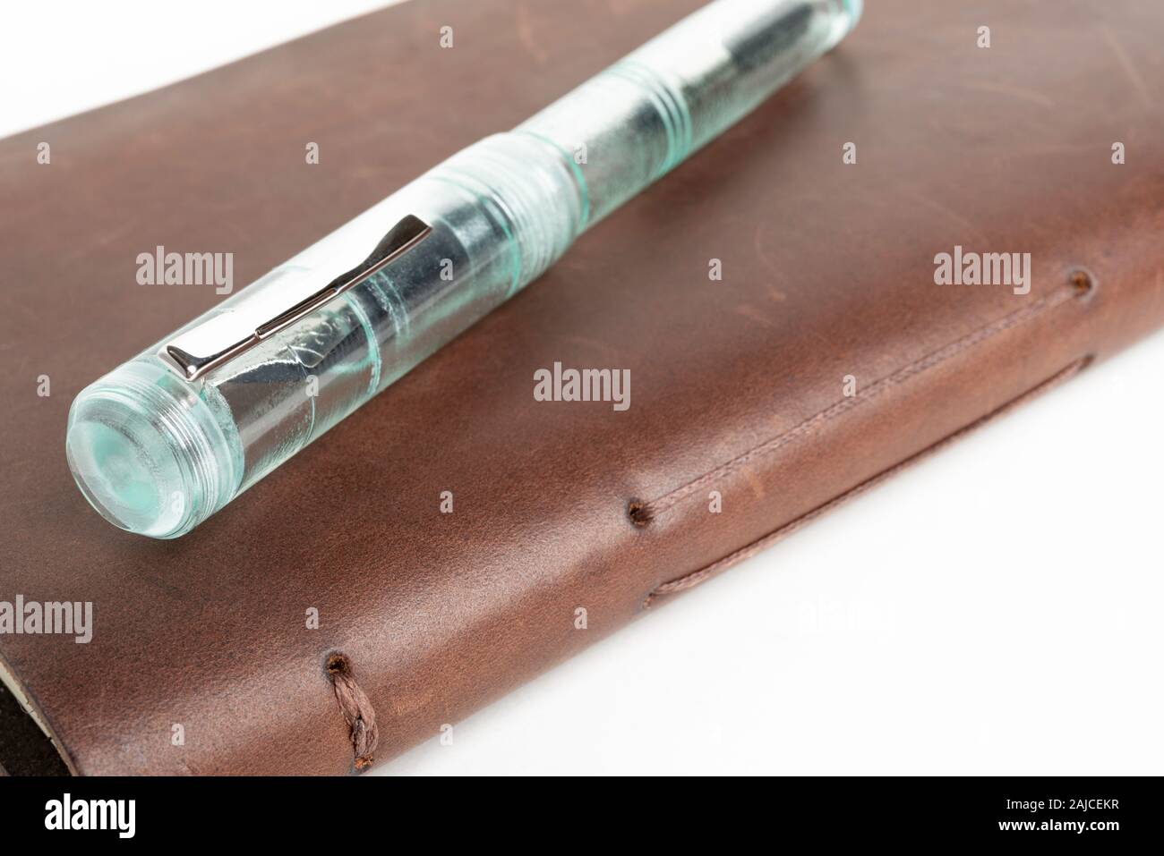Eine einfache, aber raffinierte Kombination von klassischen Leder Journal und grünem Glas Kugelschreiber auf einem weißen Hintergrund. Stockfoto
