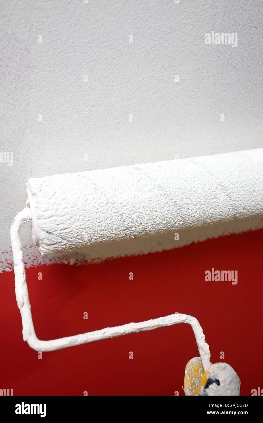 Weiß waschen über rote Farbe mit Rolle Stockfoto