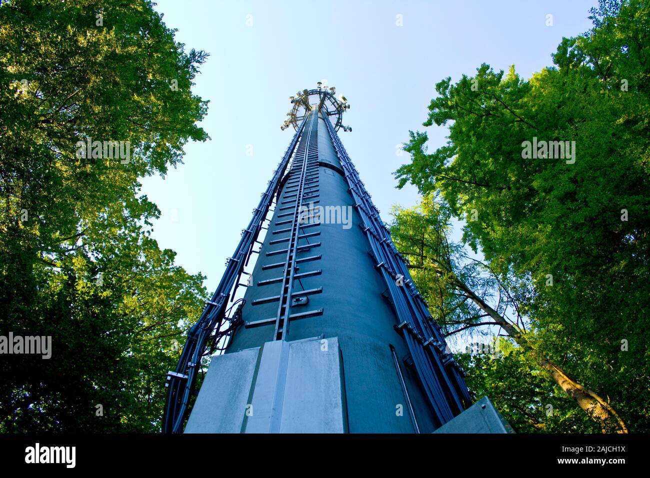 Telekommunikation Mast und grüne Bäume am blauen Himmel Stockfoto