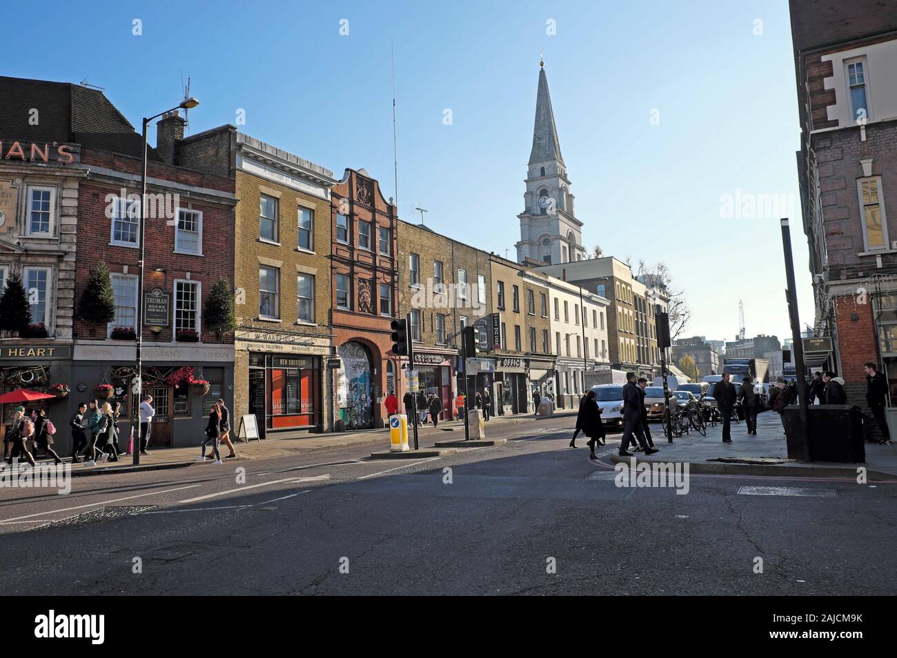 Blick auf die Straße von Menschen zu Fuß auf die Straße und die Turmspitze der Kirche Christi Gebäude in Spitalfields East London E1 England UK KATHY DEWITT Stockfoto