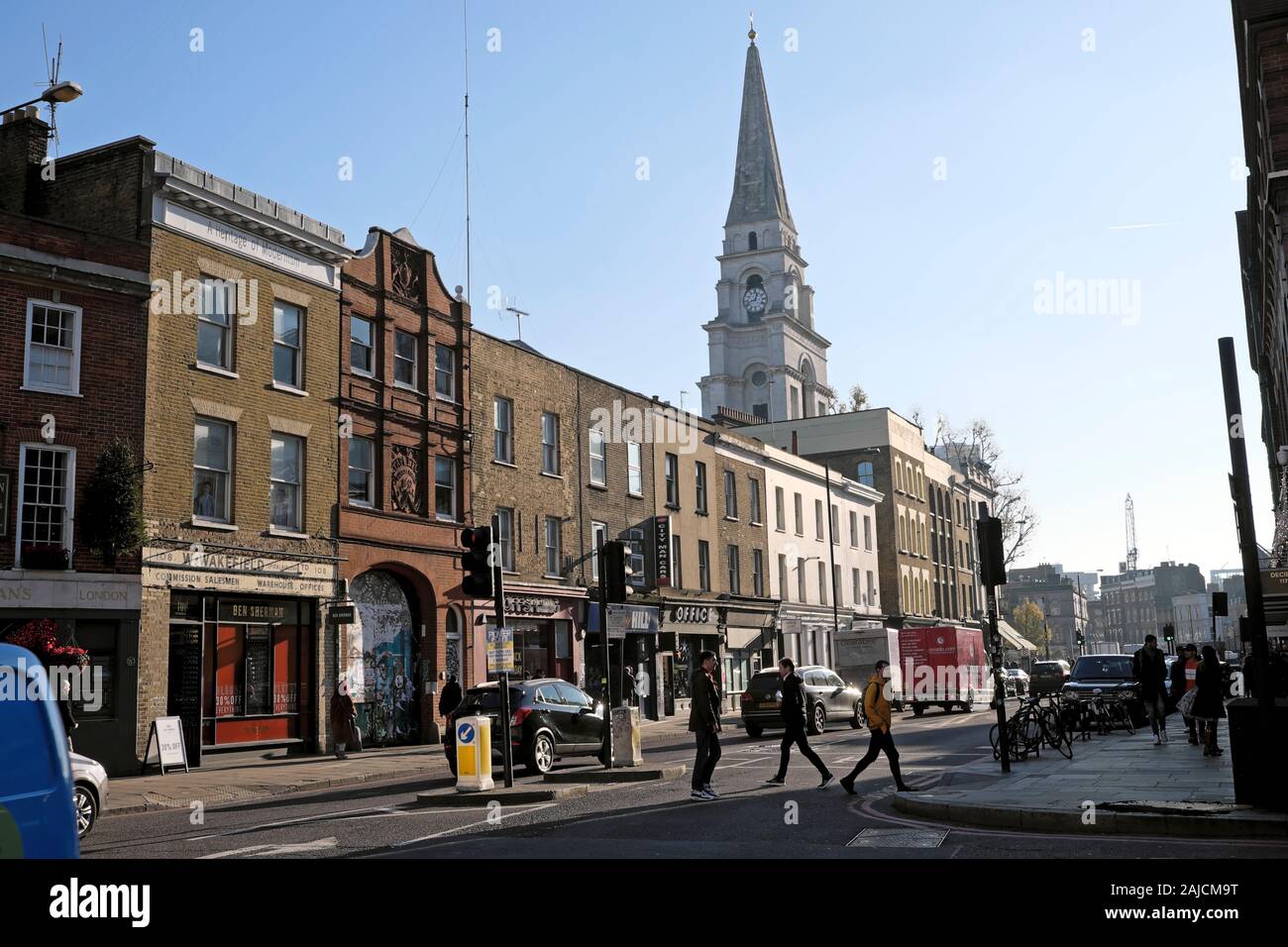 Blick auf die Straße von Menschen zu Fuß auf die Straße und die Turmspitze der Kirche Christi Gebäude in Spitalfields East London E1 England UK KATHY DEWITT Stockfoto