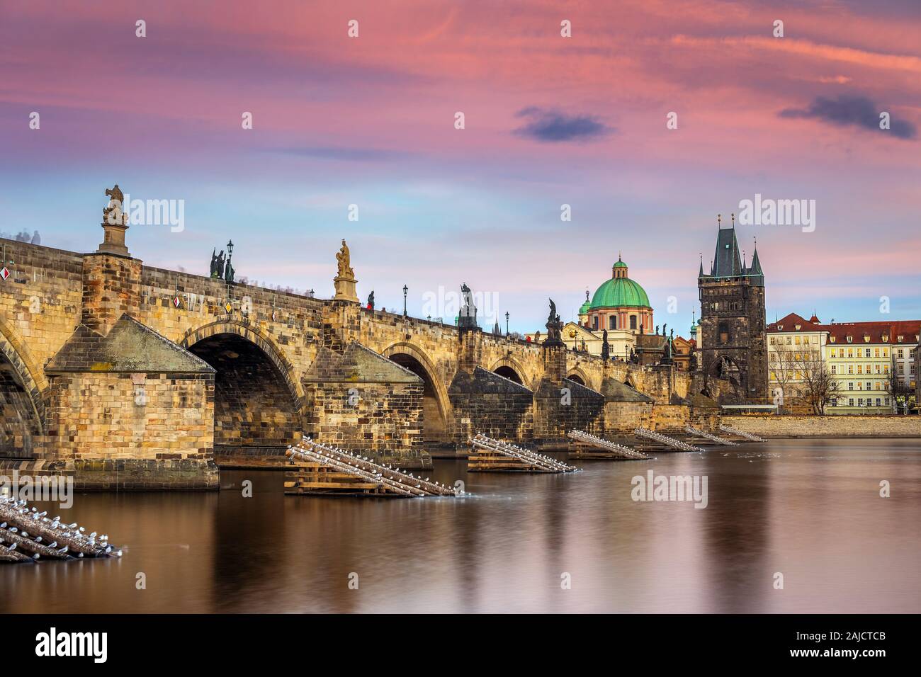 Prag, Tschechische Republik - Die weltberühmte Karlsbrücke (Karluv most) mit einem schönen violetten Himmel und Sonnenuntergang auf einer winterlichen Nachmittag Stockfoto