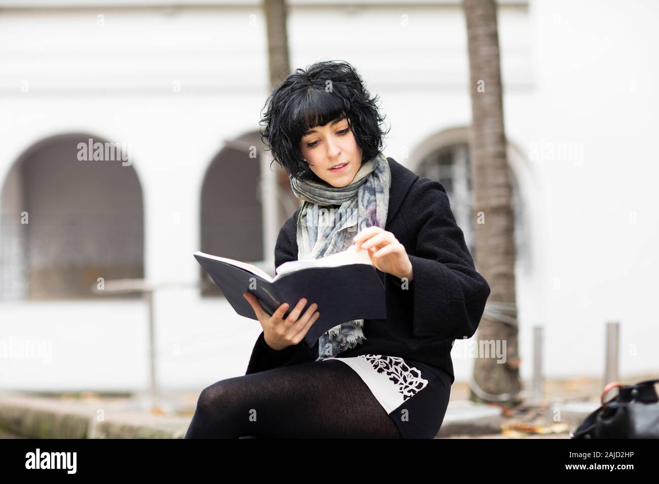 Junge Frau, die draußen in einem Buch liest Stockfoto