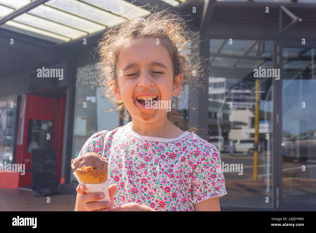 Kleines Mädchen mit unordentlichen Gesicht genießen Sie Schokolade essen in der Stadt. Stockfoto