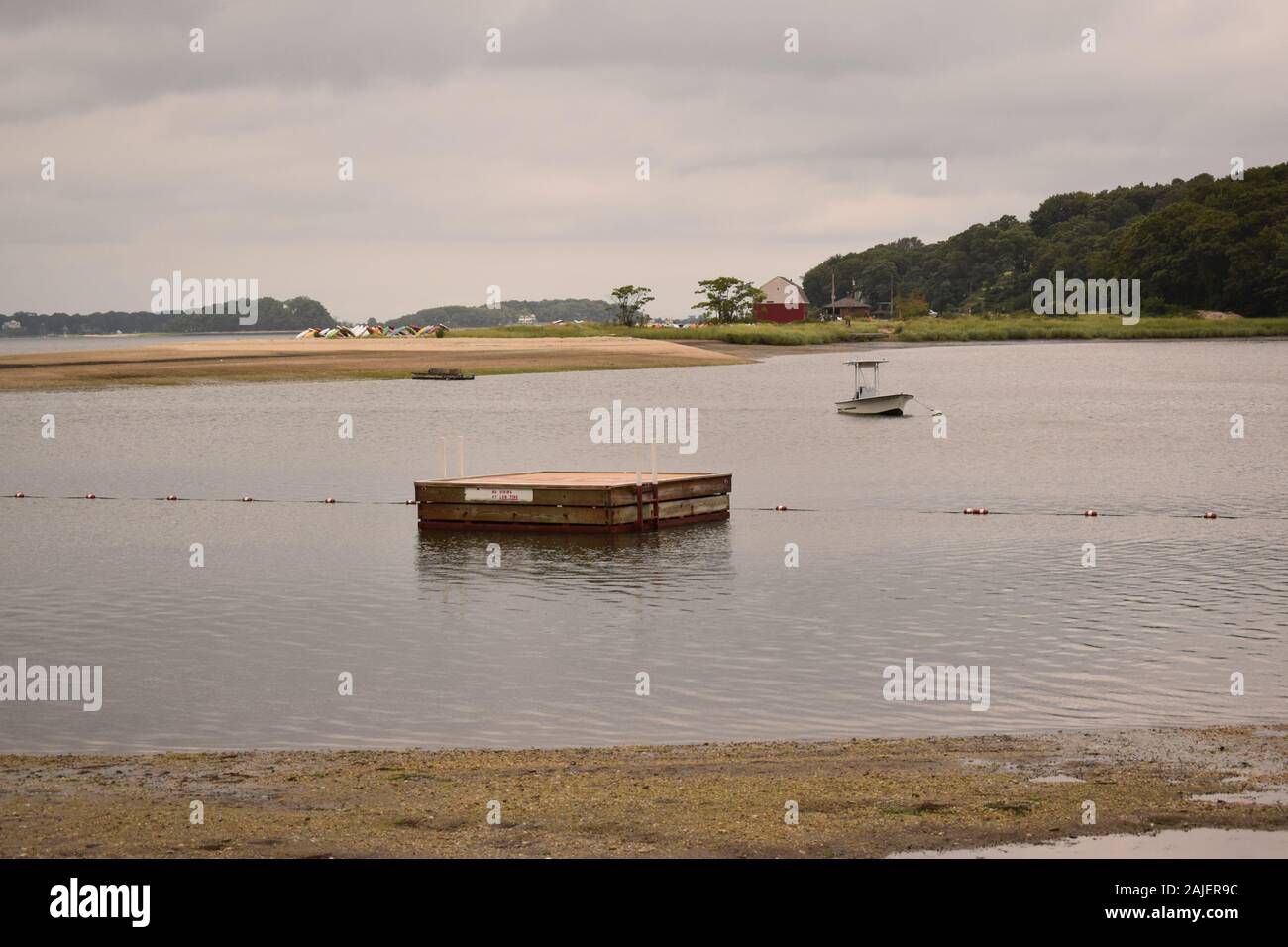 Ein schwimmdock an einem Strand mit einem roten Scheune ganz im Hintergrund. Stockfoto