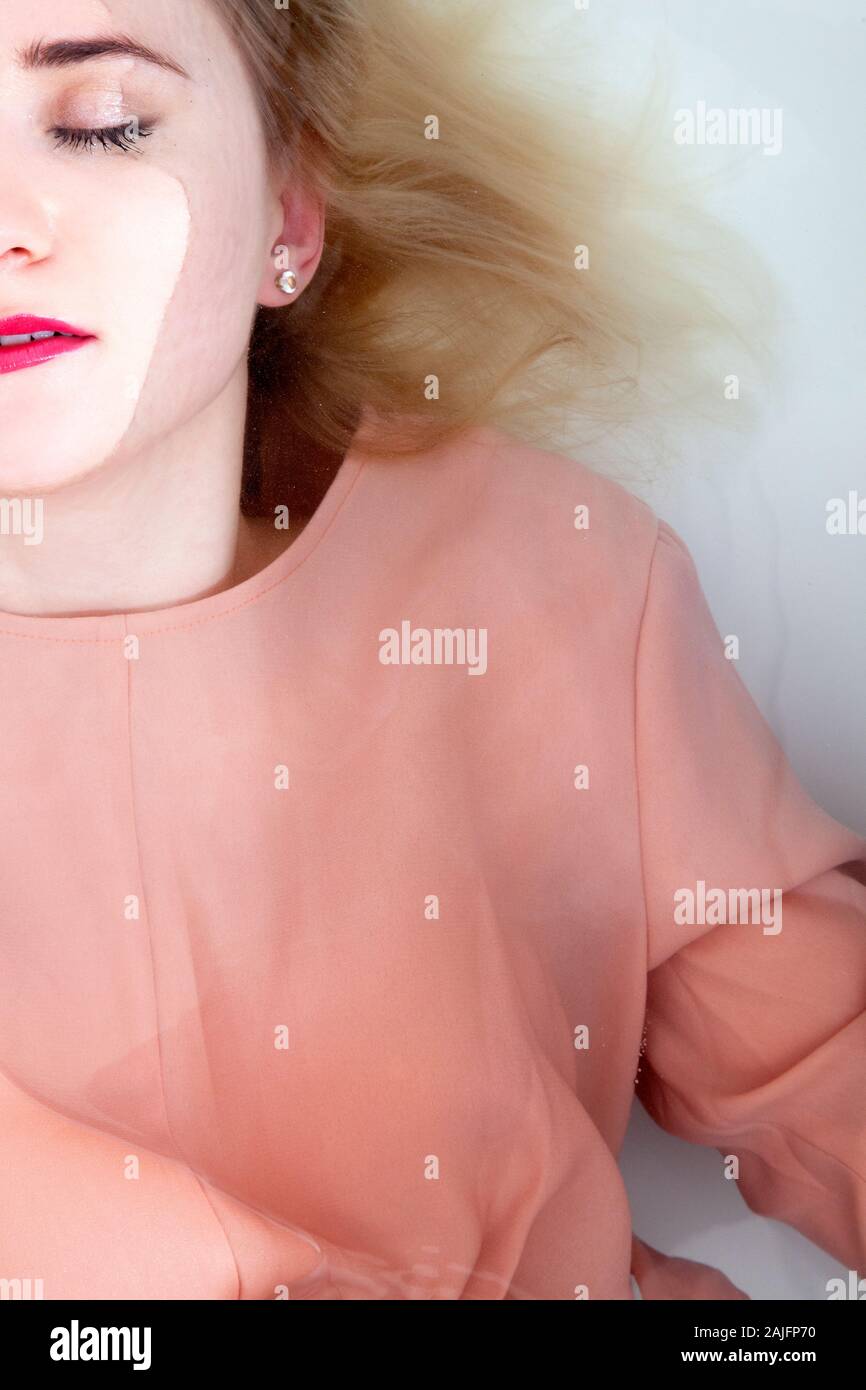 Frau im rosa Kleid liegend in der Badewanne Stockfoto