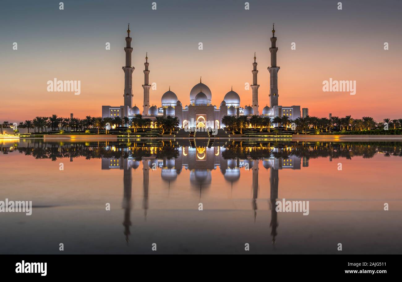 Abu Dhabi, VAE, Vereinigte Arabische Emirate: Abu Dhabi, Sheikh Zayed Moschee (auch bekannt als Grand Mosque) in der Dämmerung, der Reflexion im Wasser, bei Sonnenuntergang Stockfoto