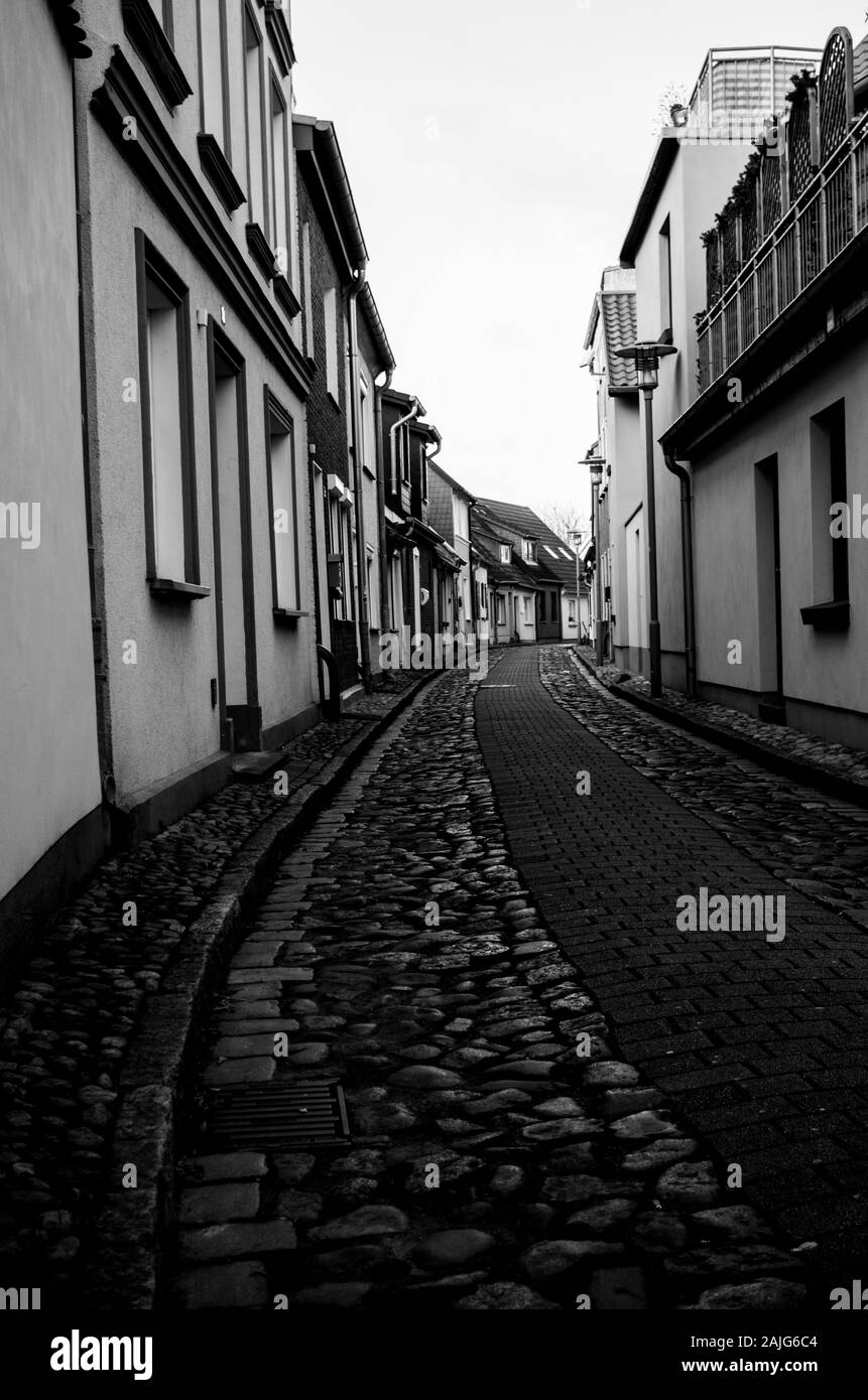 Schmale gepflasterte Straße im Meer. Romantische Straße im Stadtzentrum, ein schwarz-weiß Foto im Retro-Stil. Stockfoto