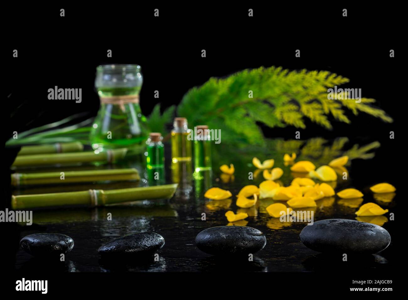Wunderschöne Spa Komposition mit Zen Basaltsteine und Bambus ätherisches Öl Pflanzen und Blumen auf schwarzem Hintergrund Stockfoto