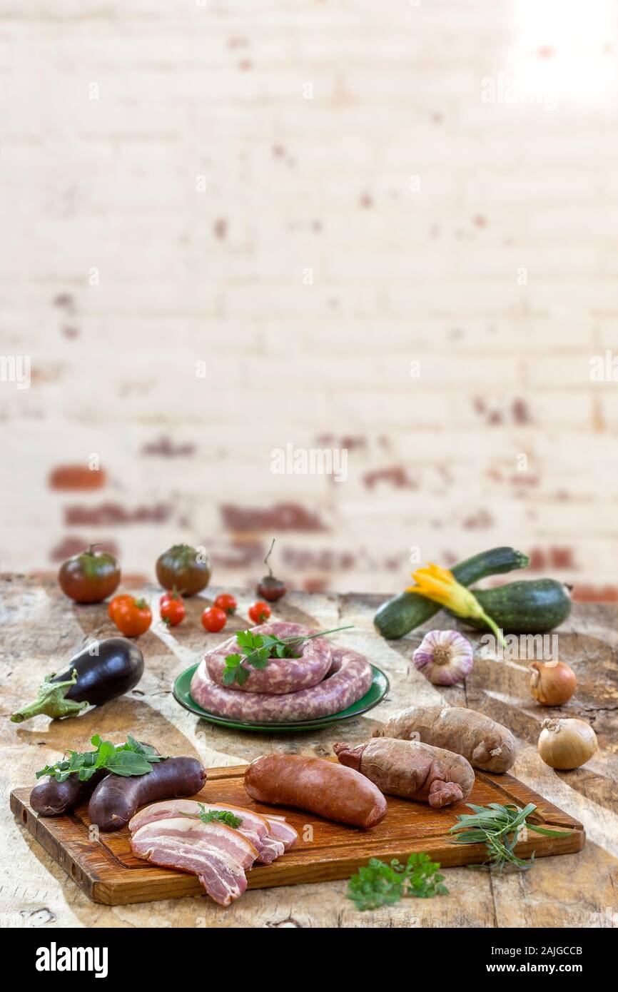 Auswahl französischer Rohwurst mit Rucola Blätter in einem Holzbrett, Gemüse auf dem Tisch auf alten weißen geknackt Red brick wall Hintergrund. Stockfoto