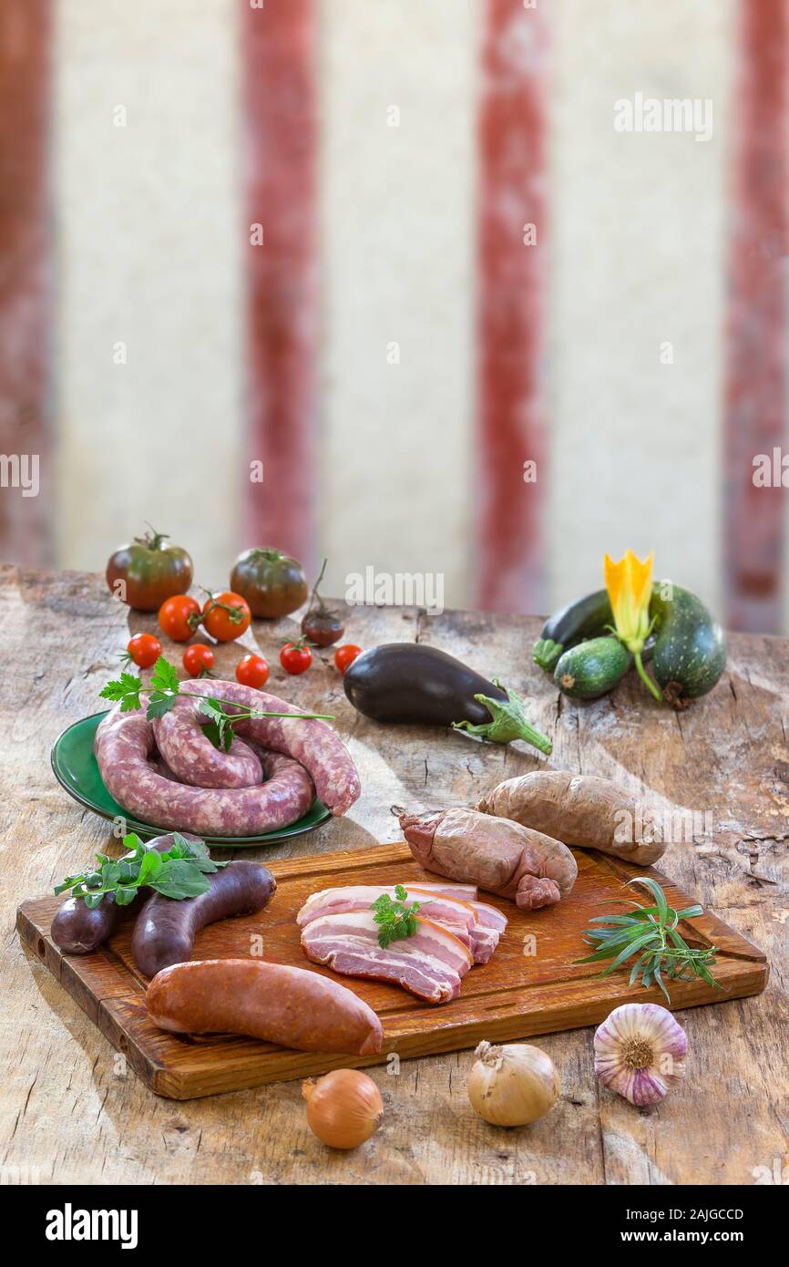 Auswahl französischer Rohwurst mit Rucola Blätter auf Holzbrett mit Gemüse auf der Tischplatte auf alten Fachwerk Wand Hintergrund isoliert. Stockfoto