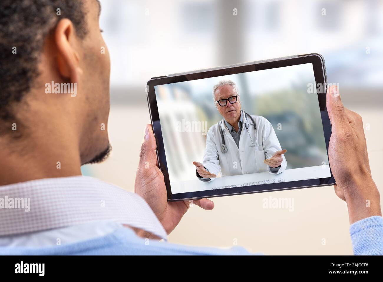 Virtuelle live Chat mit dem Patienten mit digitalen Tablet und ein Arzt über das Internet. In-home Care für eine junge männliche Patienten in der Telemedizin oder Telehealth, Stockfoto