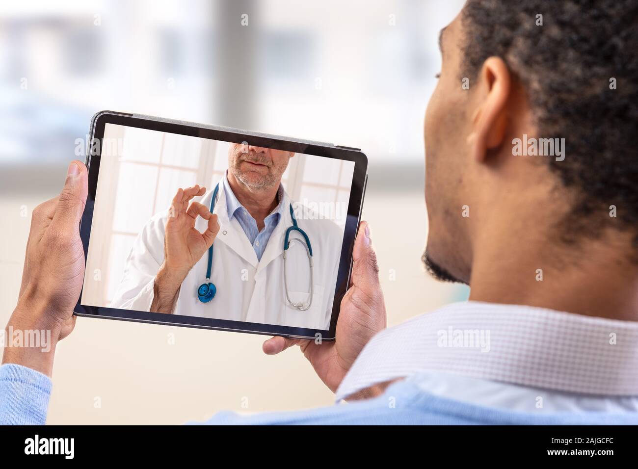 Virtuelle live Chat mit dem Patienten mit digitalen Tablet und ein Arzt über das Internet. In-home Care für eine junge männliche Patienten in der Telemedizin oder Telehealth, Stockfoto