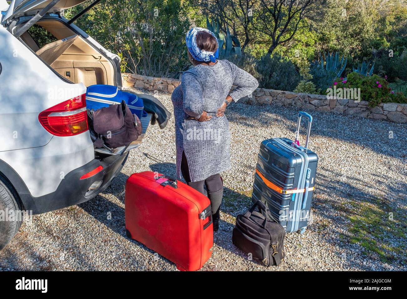 Reisen und Lifestyle Konzept: Frau mit Rückenschmerzen laden die Koffer im Auto Stockfoto