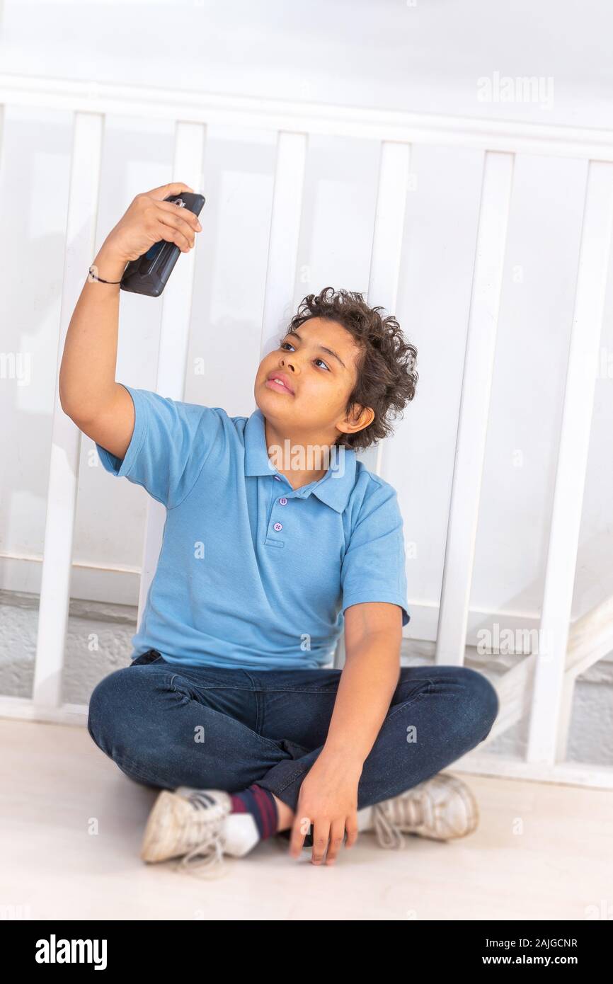 Porträt eines attraktiven Teenager boy Holding sein Smartphone mit seiner Hand und ein selfie von sich selbst Indoor Stockfoto
