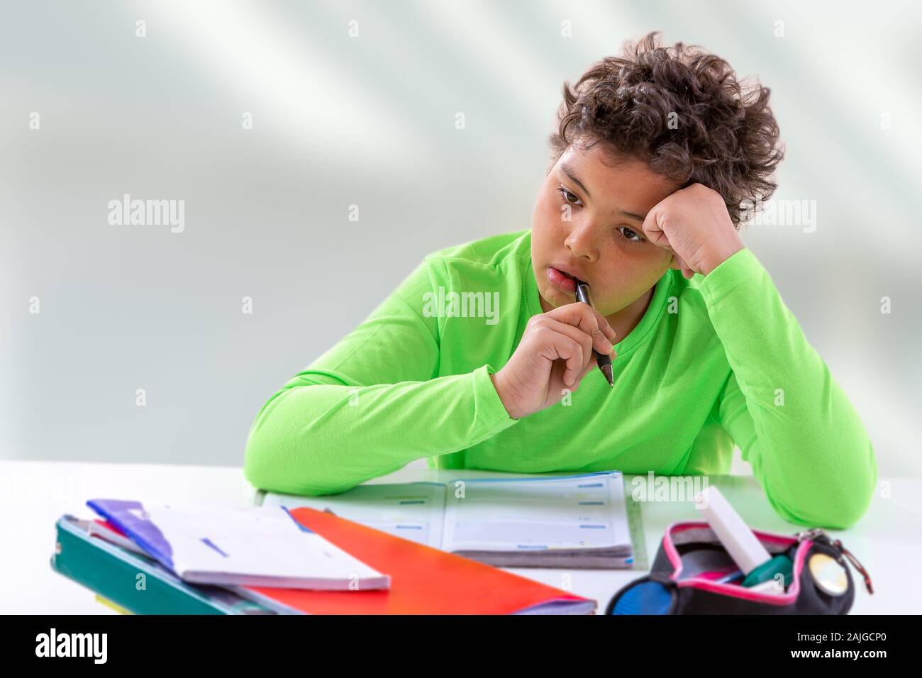 Netter Junge im Raum: der Junge hat ein nachdenklicher Blick und er sitzt am Tisch, Hausaufgaben Stockfoto