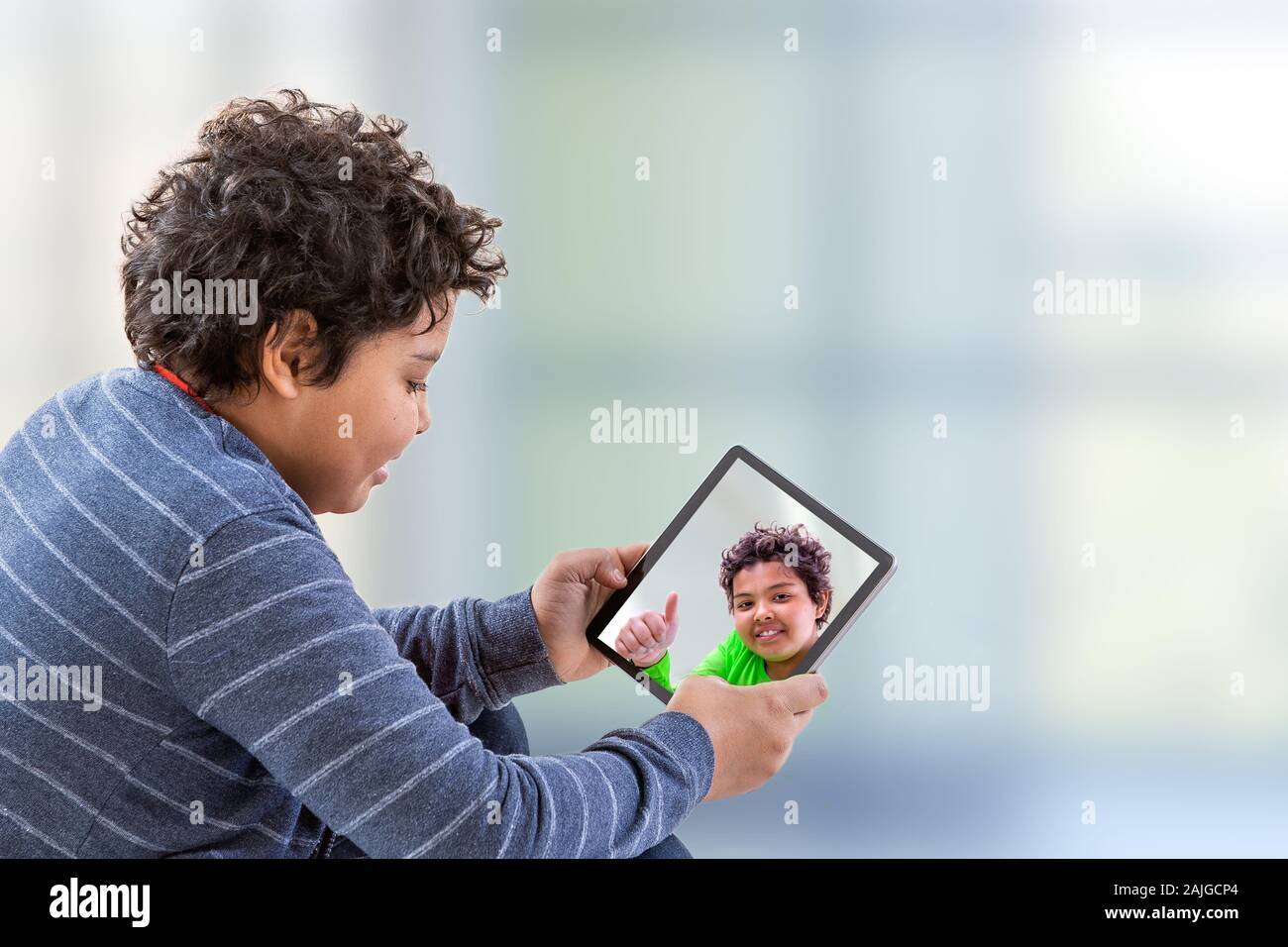 Jugendlich junge watcning Fotos auf digitale Tablette, mit Blick auf dem Bildschirm Stockfoto Jugendlich junge watcning Fotos auf digitale Tablette, mit Blick auf dem Bildschirm Stockfoto