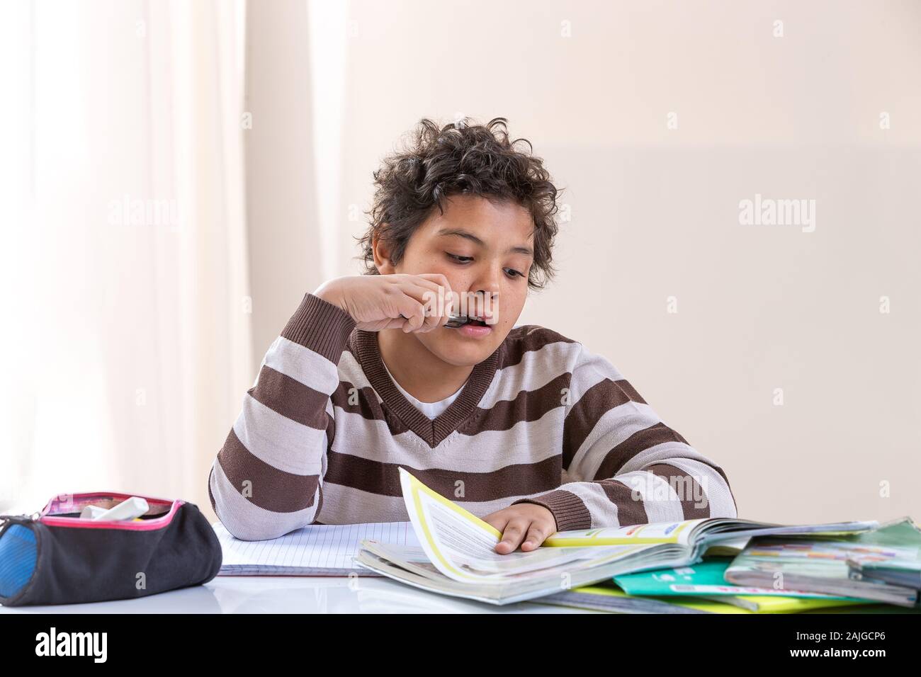 Netter Junge im Raum: der Junge hat ein nachdenklicher Blick und er sitzt am Tisch, Hausaufgaben Stockfoto