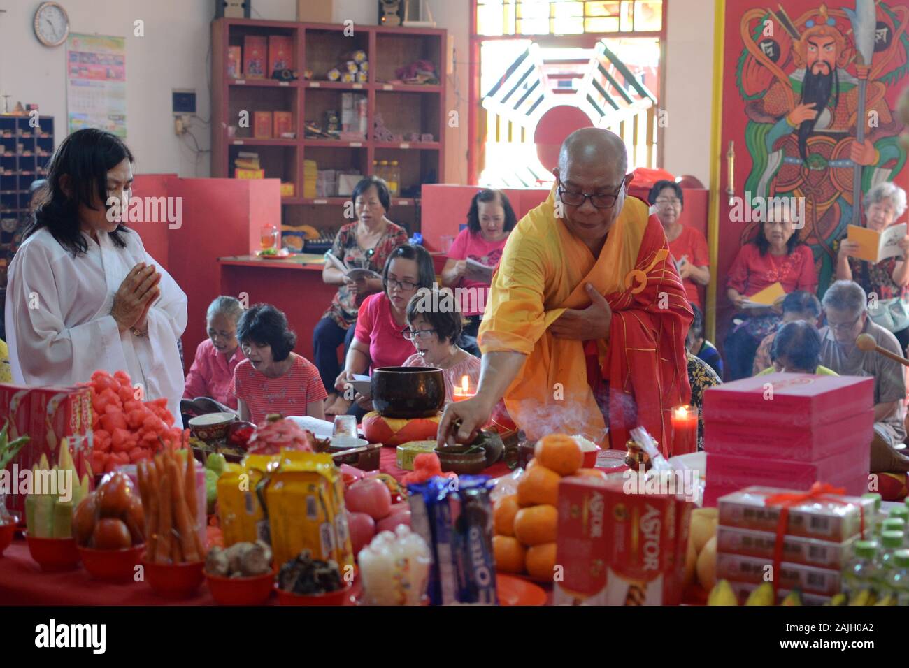 Ein buddhistischer Priester leitet vor dem chinesischen Neujahrsfest eine Gebetszeremonie vor einem Altar mit Opfergaben. Stockfoto