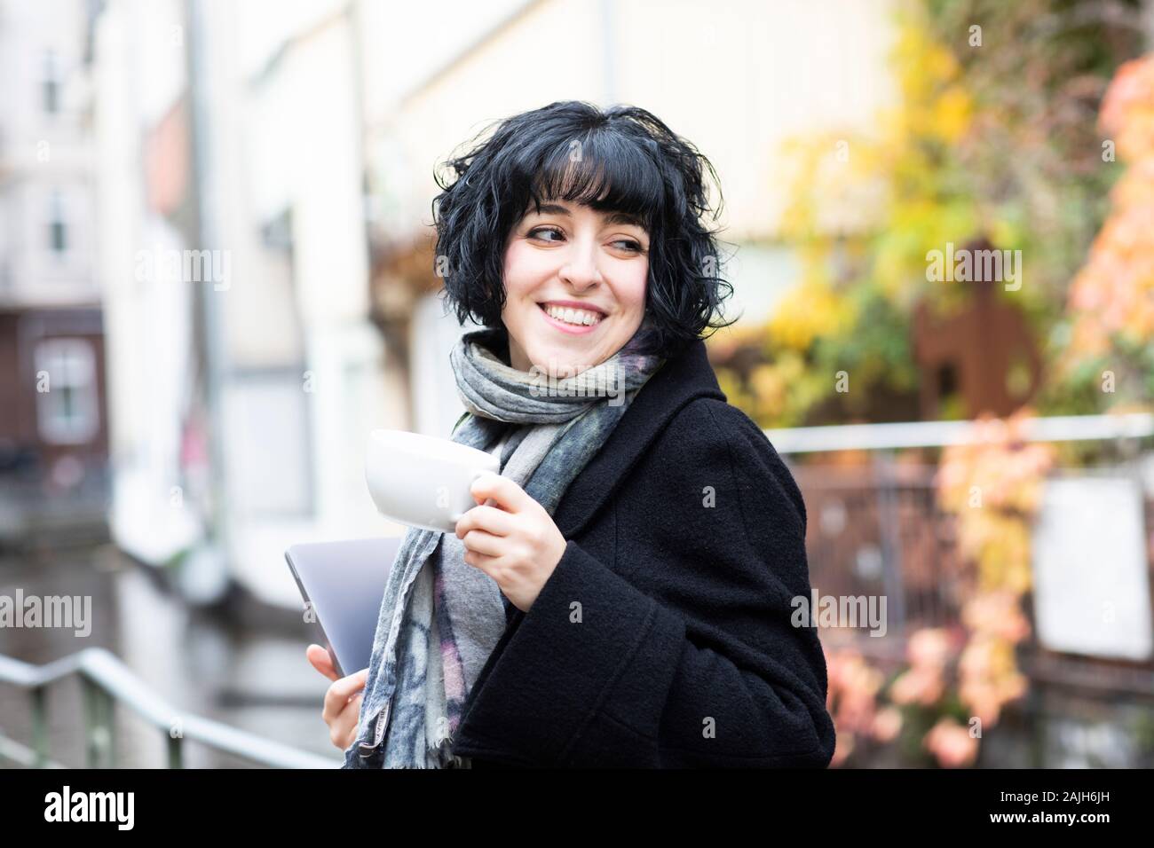 Junge Frau arbeitet und trinkt Kaffee draußen Stockfoto