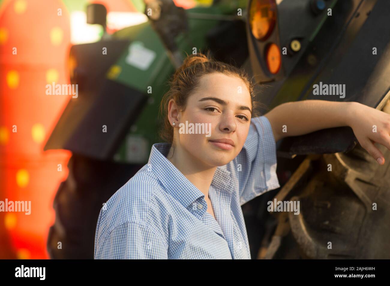Bäuerin lächelnd vor einem Traktor Stockfoto