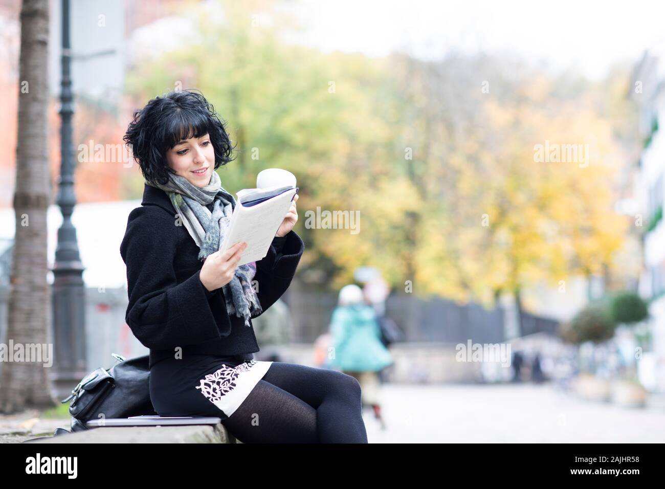 Junge Frau, die draußen in einem Buch liest Stockfoto