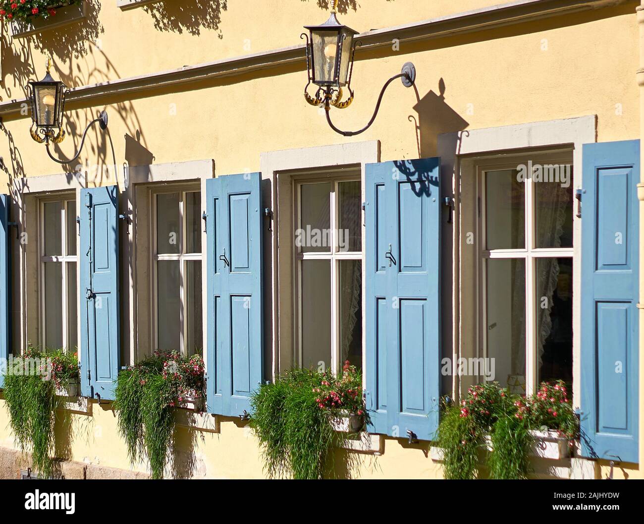 Hübsche Fenster mit Blumenkästen, die mit schönen Pflanzen umgeben sind, im mittelalterlichen Touristenort Rothenburg ob der Tauber in Deutschland. Stockfoto