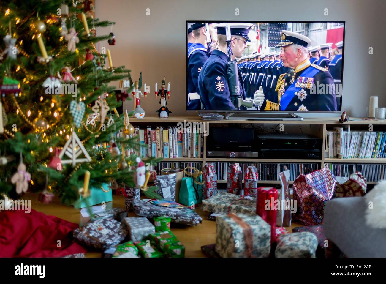 Weihnachtsgeschenke bleibt ungeöffnet unter einem Weihnachtsbaum und Footage von Prinz Charles treffen Mitglieder des Militärs während der Rede der Königin der Nation am Weihnachtstag, eine Tradition, die im Jahre 1932 begonnen und die erste Sendung im Fernsehen im Jahre 1957, am 25. Dezember 2019 in Bristol, England. Stockfoto