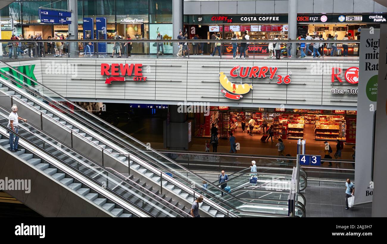 Bunte Geschäfte auf zwei Ebenen mit Rolltreppen im modernen Berliner  Hauptbahnhof. Rewe Lebensmittelgeschäft und Curry 36 fast Food  Stockfotografie - Alamy