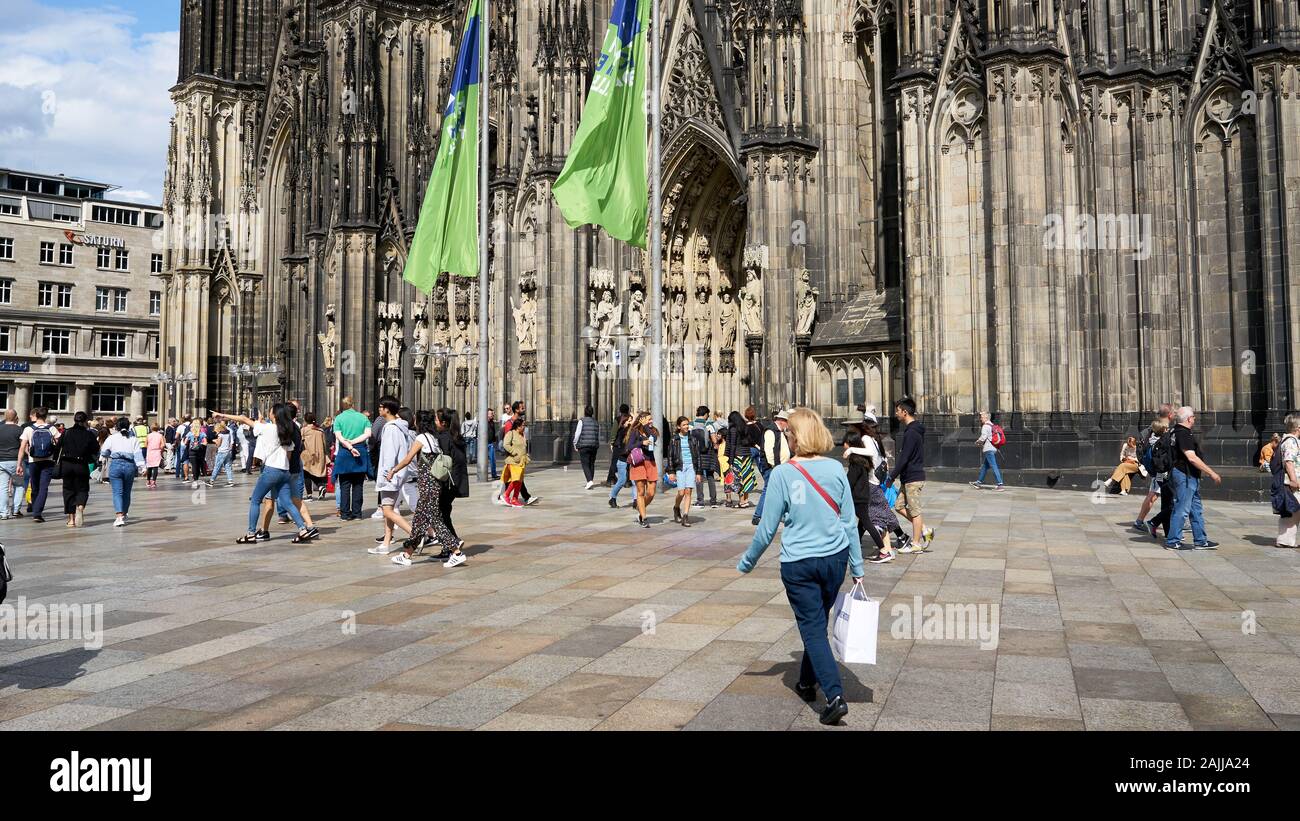 Touristen und Käufer genießen die Zeit auf dem Platz vor der beeindruckenden gotischen Kölner Dom in Deutschland. Stockfoto