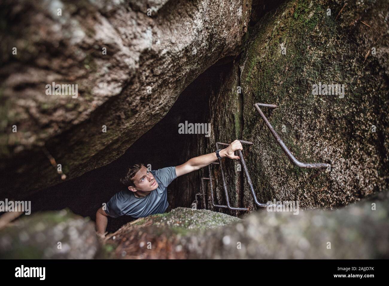 Ein Mann klettert aus einer dunklen Höhle, Millinocket, Maine, auf Leitersprossen Stockfoto