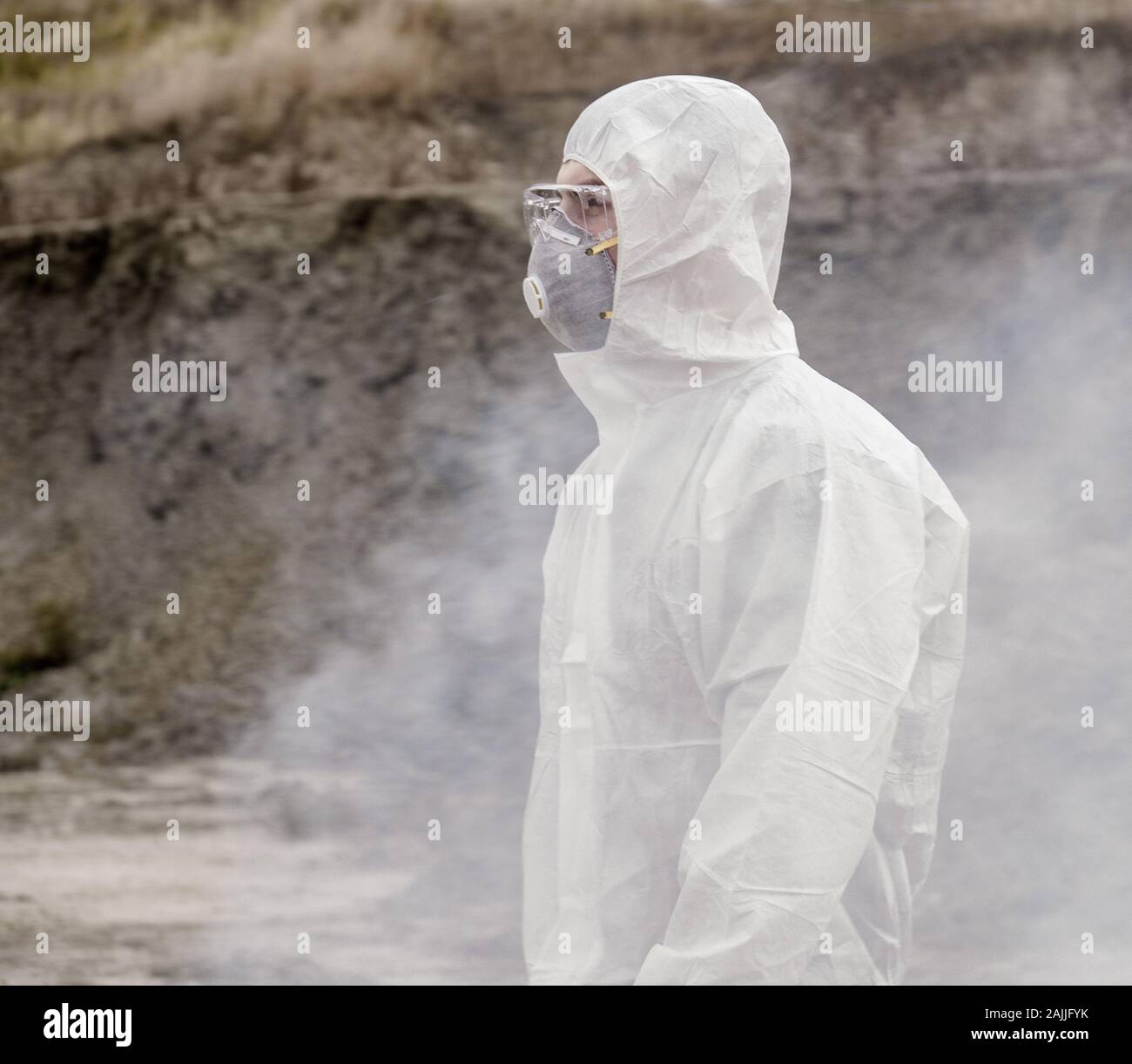 Lab Techniker in einer Maske und Schutzanzug gegen Chemikalien, Spaziergänge auf trockenem Boden mit einem tool box durch giftigen Rauch Stockfoto