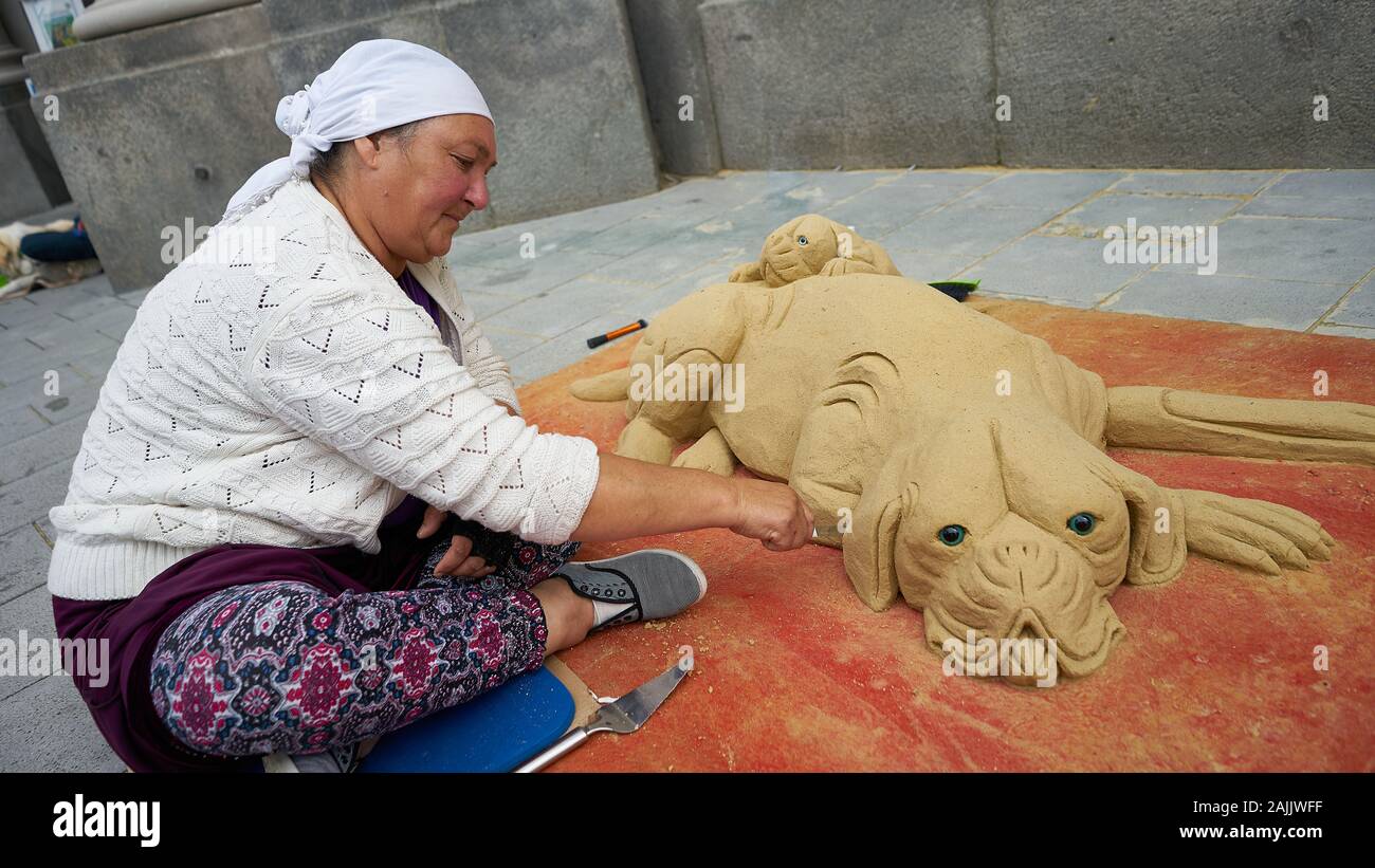 Münchner Street-Szene mit Künstlerin macht Hund und Welpen Sandskulptur auf der Fußgängerzone in der Münchner Innenstadt Stockfoto