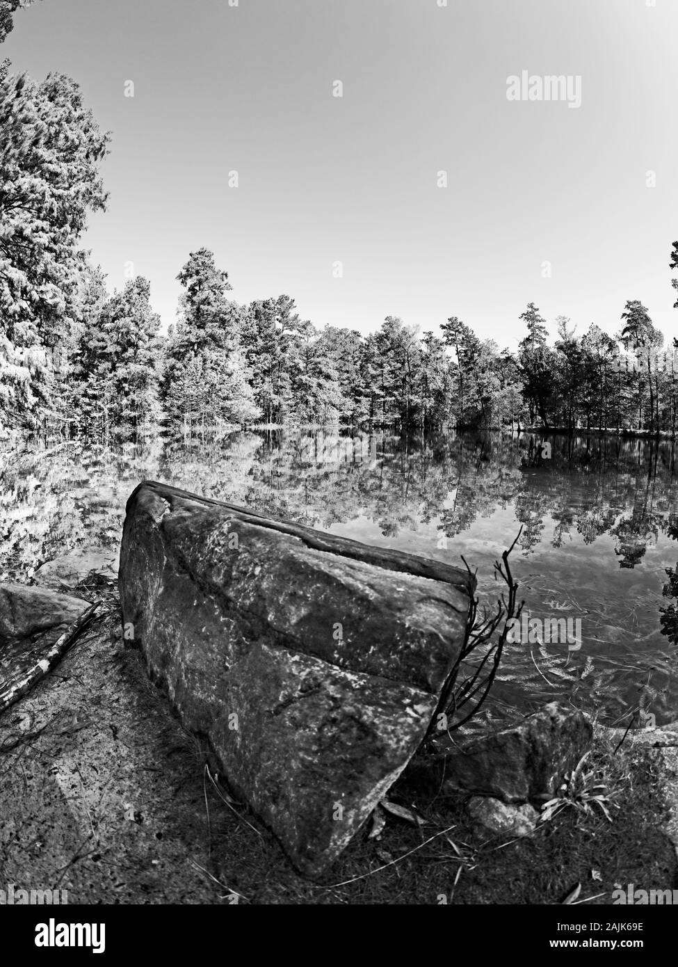 Conroe, TX USA - 11/15/2019 - Rock am See mit Fall farbige Bäume in B&W Stockfoto