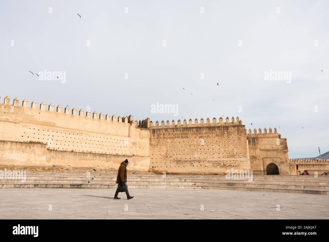 Herzlich gekleideter Einzelmann, der in der Landschaft des Boujloud-Platzes (auch Place Bou Jeloud oder Place Boujloud) und der Stadtmauern von Fes (Fez), Marokko, spazieren geht Stockfoto