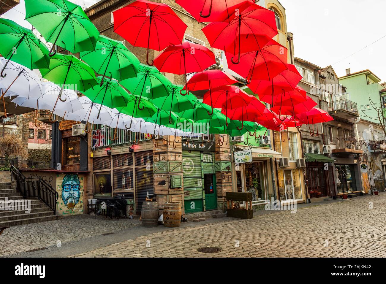 Straße und Häuser im Bezirk Kapana, Stadt von Plovdiv, Bulgarien. Bunte Sonnenschirme mit Weiß, Grün, Rot Farben aus bulgarische Flagge Stockfoto