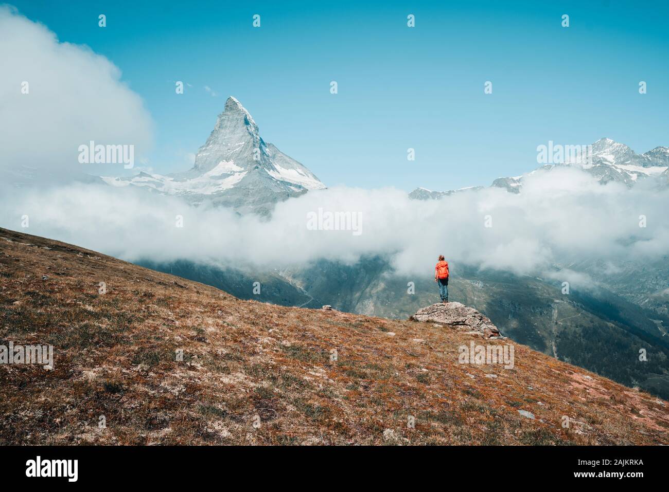 Yong Frau auf Felsen vor dem Matterhorn über Wolken Stockfoto