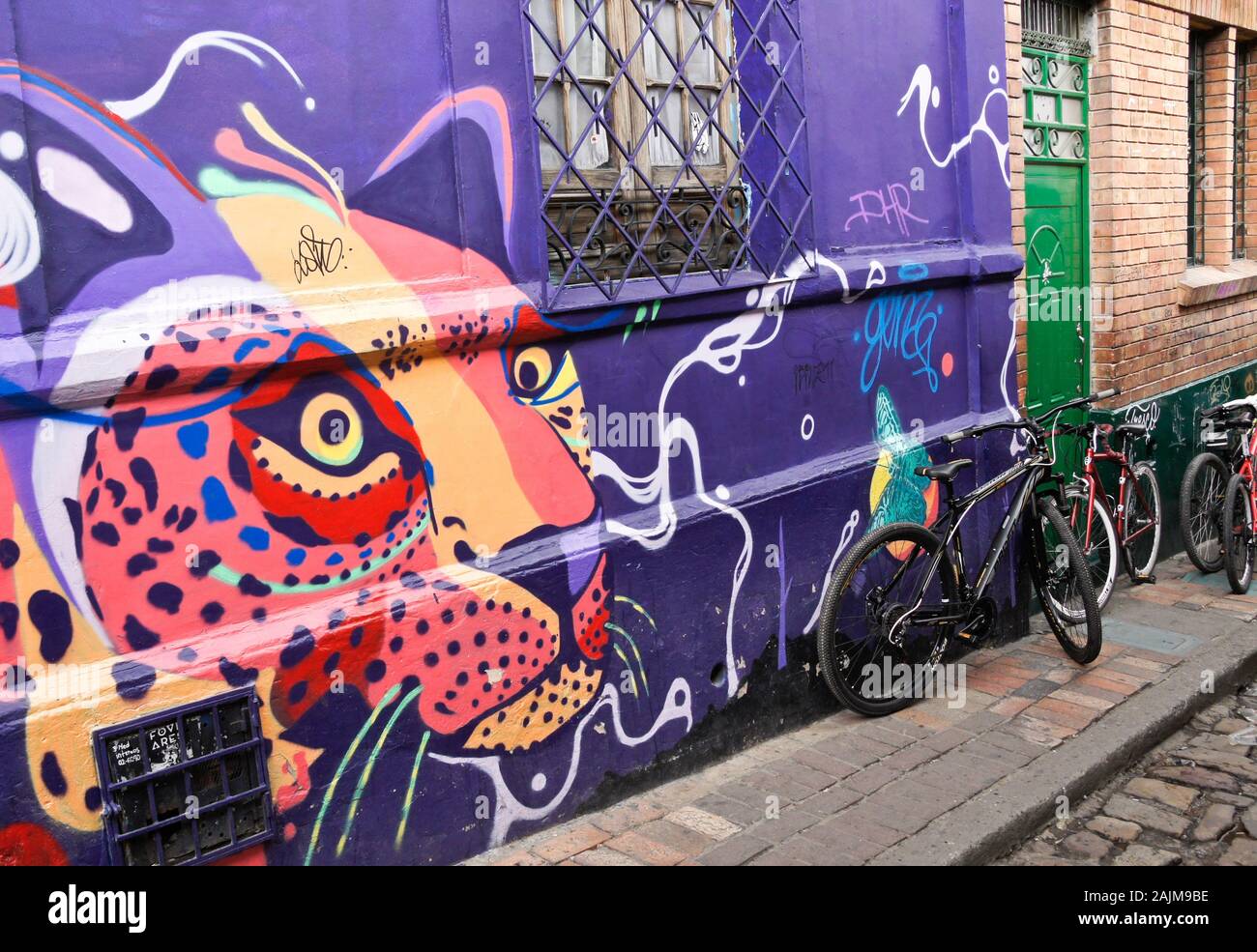 Fahrräder, die vor dem Casa Bellavista Hostel geparkt wurden und mit Straßenkunst und Graffiti dekoriert sind, befinden sich an der Calle del Embudo, La Candelaria, Bogota, Kolumbien Stockfoto