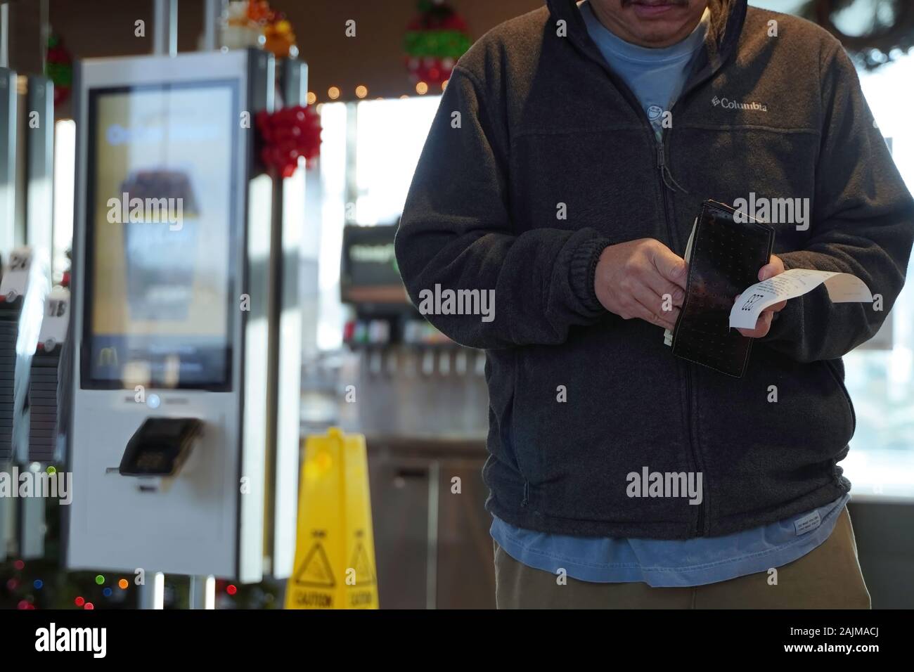 Cromwell, CT/USA - November 25, 2019: Asiatischer mann Sortieren durch Geld in der Brieftasche nach Essen bestellen bei McDonalds Stockfoto