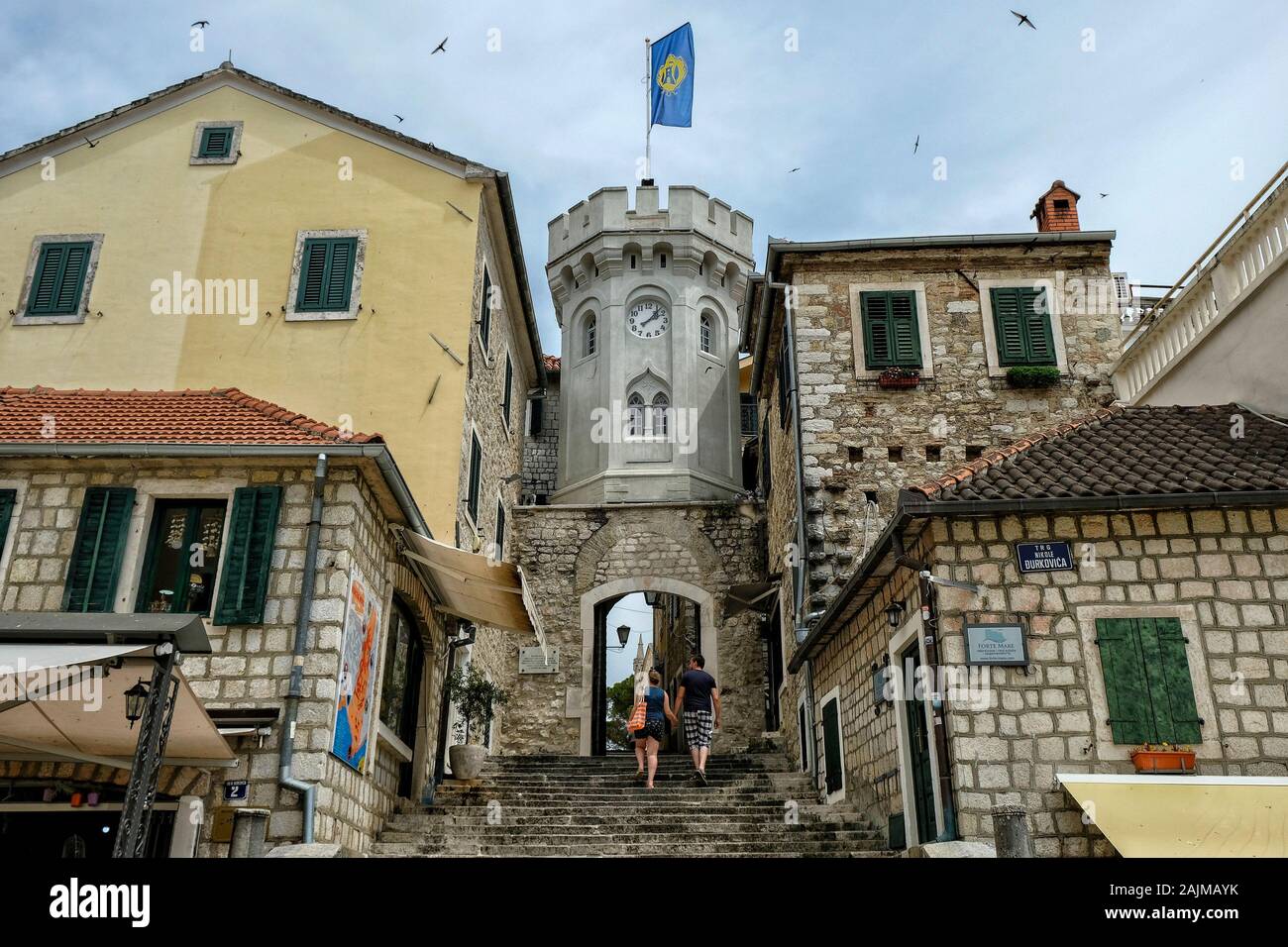 Herceg Novi, Montenegro - Juni 2019: Touristen im alten Stadttor mit dem kleinen Uhrturm umgeben von alten Häusern am 22. Juni 2019 in Montenegro Stockfoto