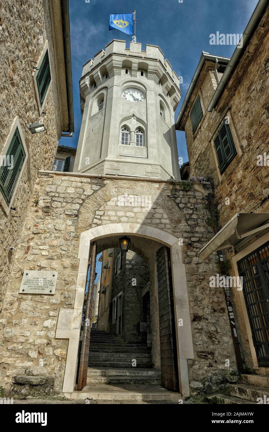 Herceg Novi, Montenegro - Juni 2019: Altes Stadttor mit dem kleinen Uhrturm umgeben von alten Häusern am 22. Juni 2019 in Herceg Novi, Montenegro. Stockfoto