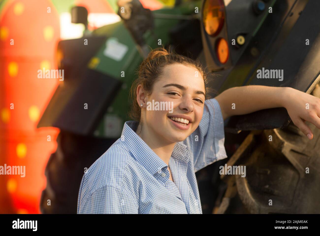 Bäuerin lächelnd vor einem Traktor Stockfoto