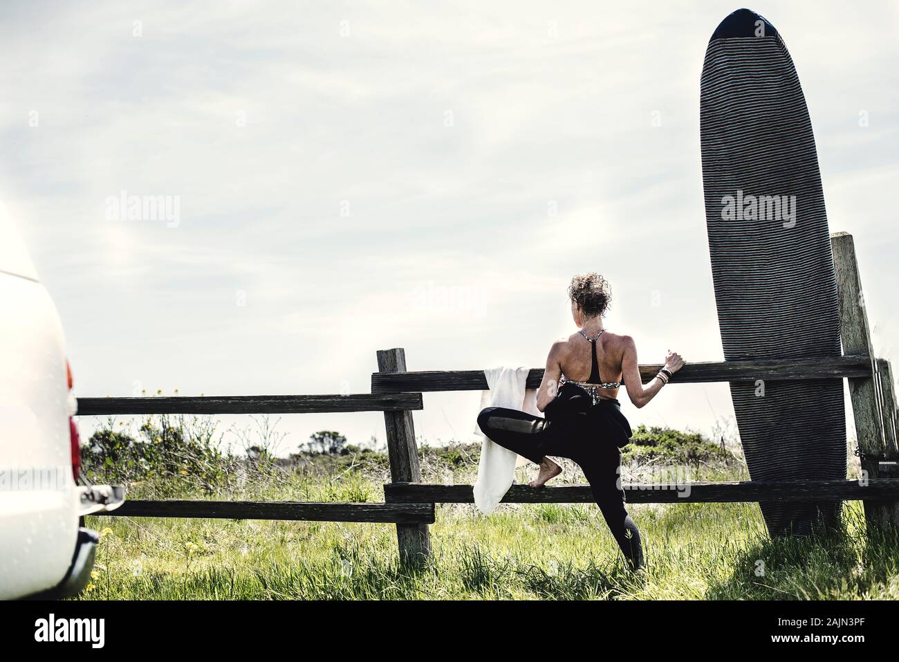 Weibliche Surfer erstreckt sich vor dem Surfen Stockfoto
