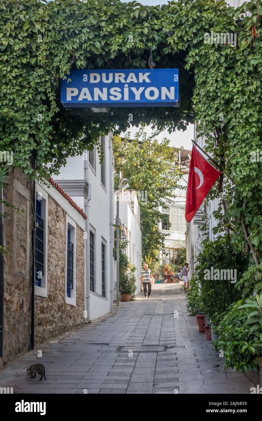 Bodrum, Türkei - 26. September 2019: Menschen auf dem Weg nach unten eine Straße führt zu einem kleinen Hotel oder Pension. Es gibt viele Hotels in der Stadt. Stockfoto