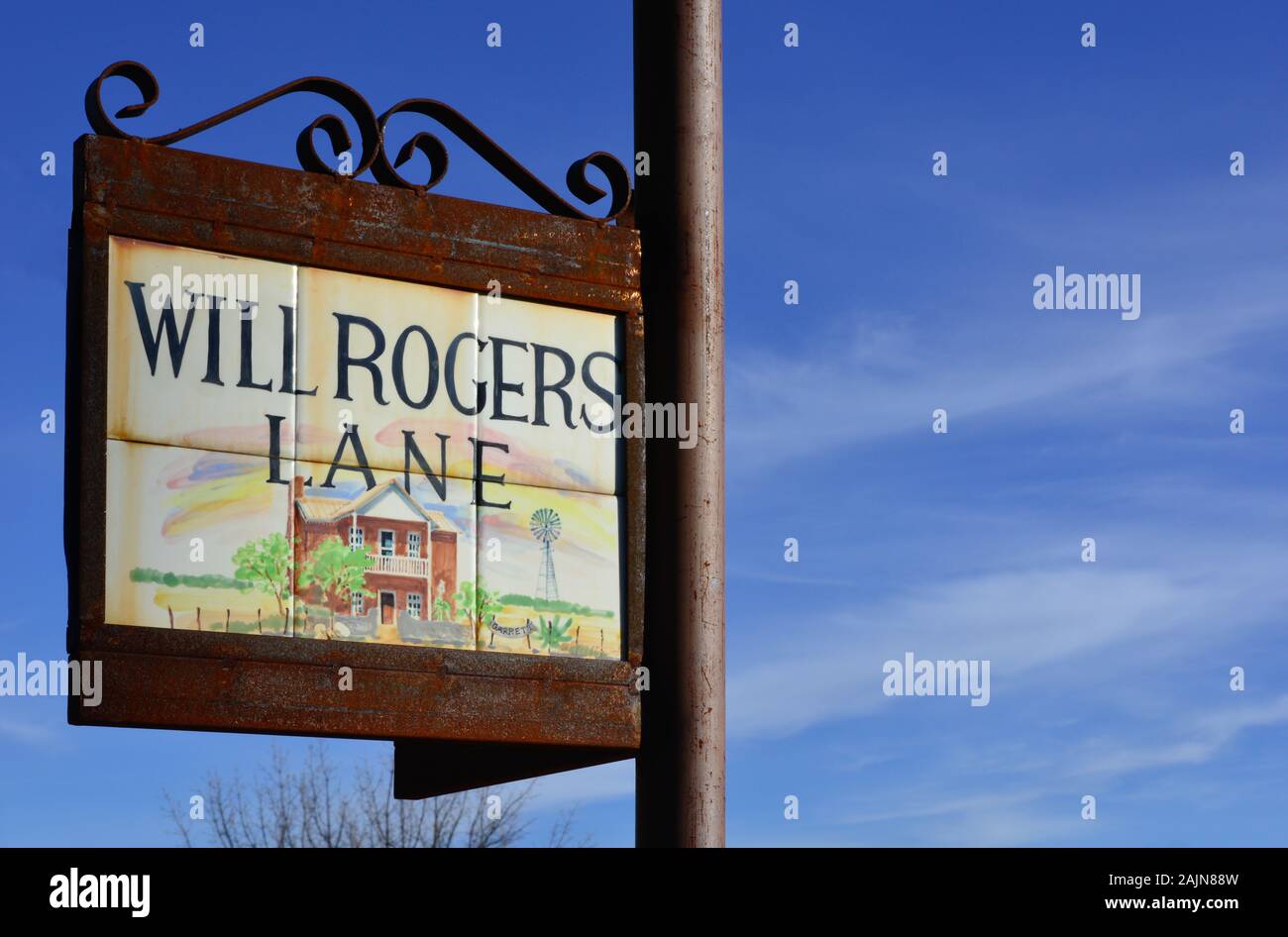 In der Nähe von malerischen Fliesen, Garrett House in einem reich verzierten Metall schild Halter lesen Will Rogers Lane gerahmt, vor blauem Himmel in Tubac, AZ Stockfoto
