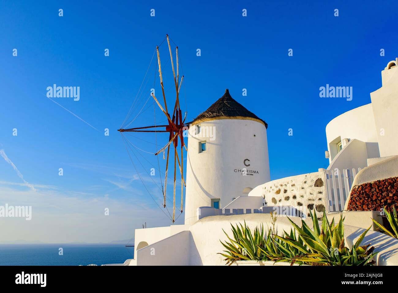 Windmühle und traditionelles weißes Gebäude mit Blick auf die Ägäis in Oia, Santorini, Griechenland Stockfoto
