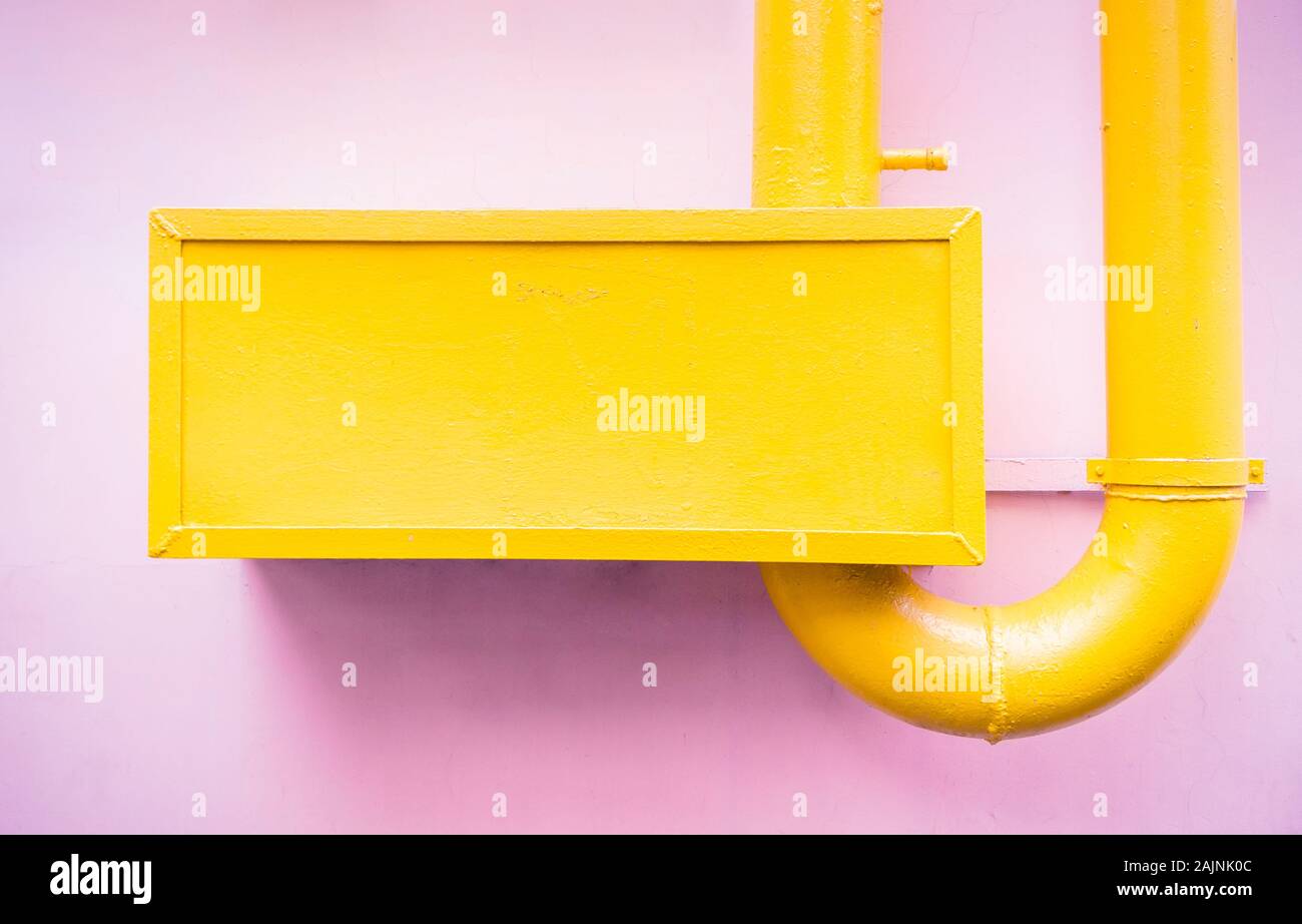 Eingängige Zusammenfassung minimalistischen Stil gelb lackiert Rohrleitungen auf der Oberfläche der Rosa pastellfarbenen Wand Stockfoto