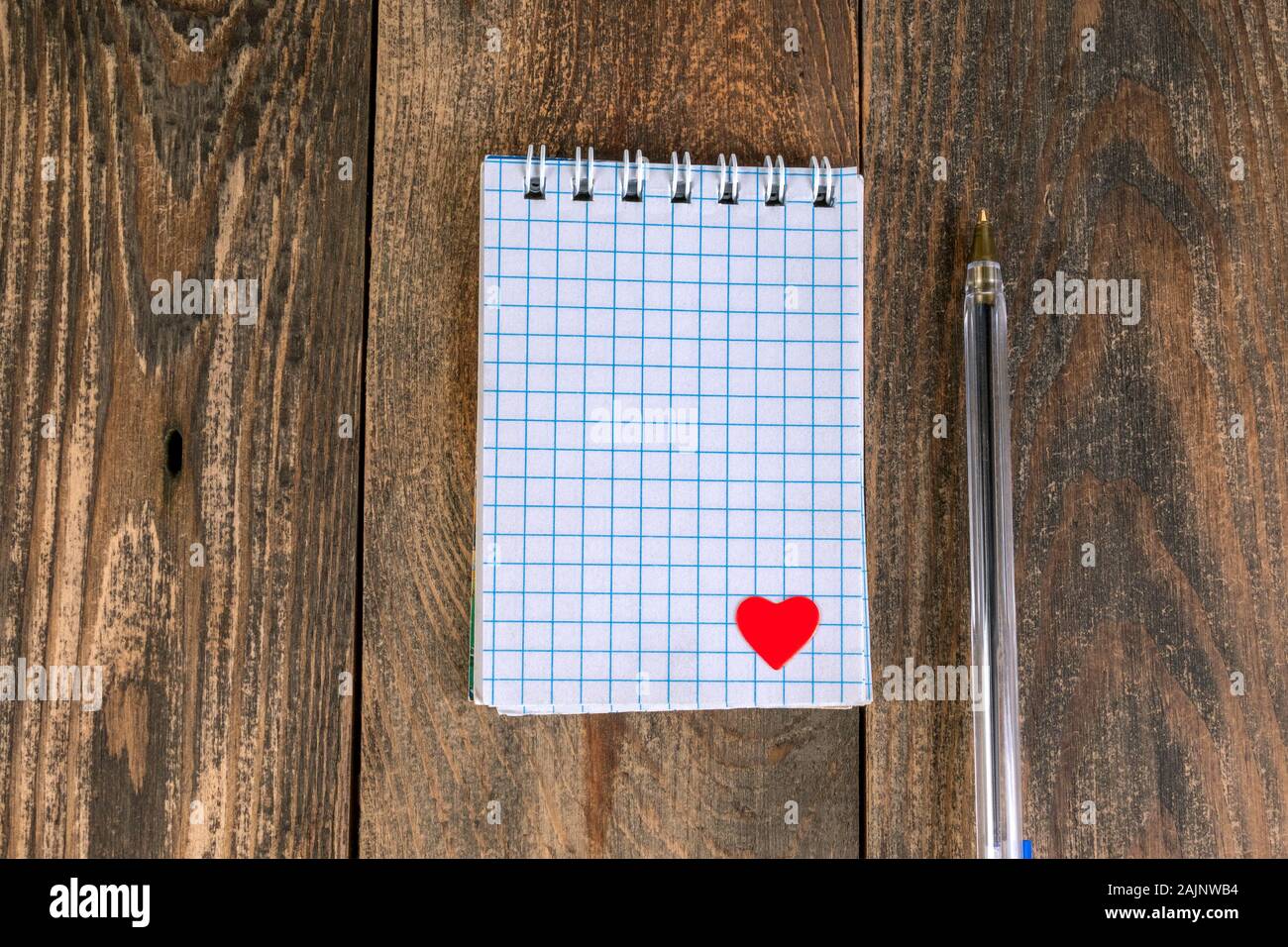 Merkzettel in den Käfig, mit kleinen Herzen in der unteren Ecke und Stift, liegt auf Holztisch. Das Konzept der Valentines Tag Urlaub oder eine Erinnerung an Liebe zu jemand. Stockfoto