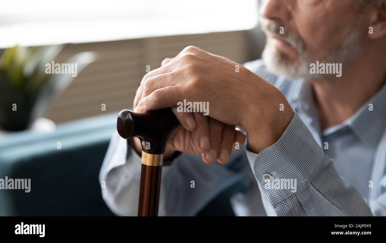 Ältere Mann sitzt drinnen closeup Fokus auf Hände, die Zuckerrohr Stockfoto